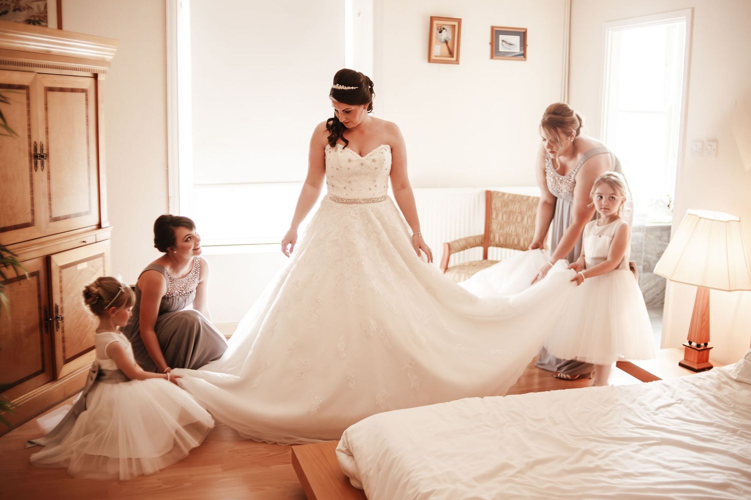 Bridesmaids helping the bride arrange the train of her wedding dress