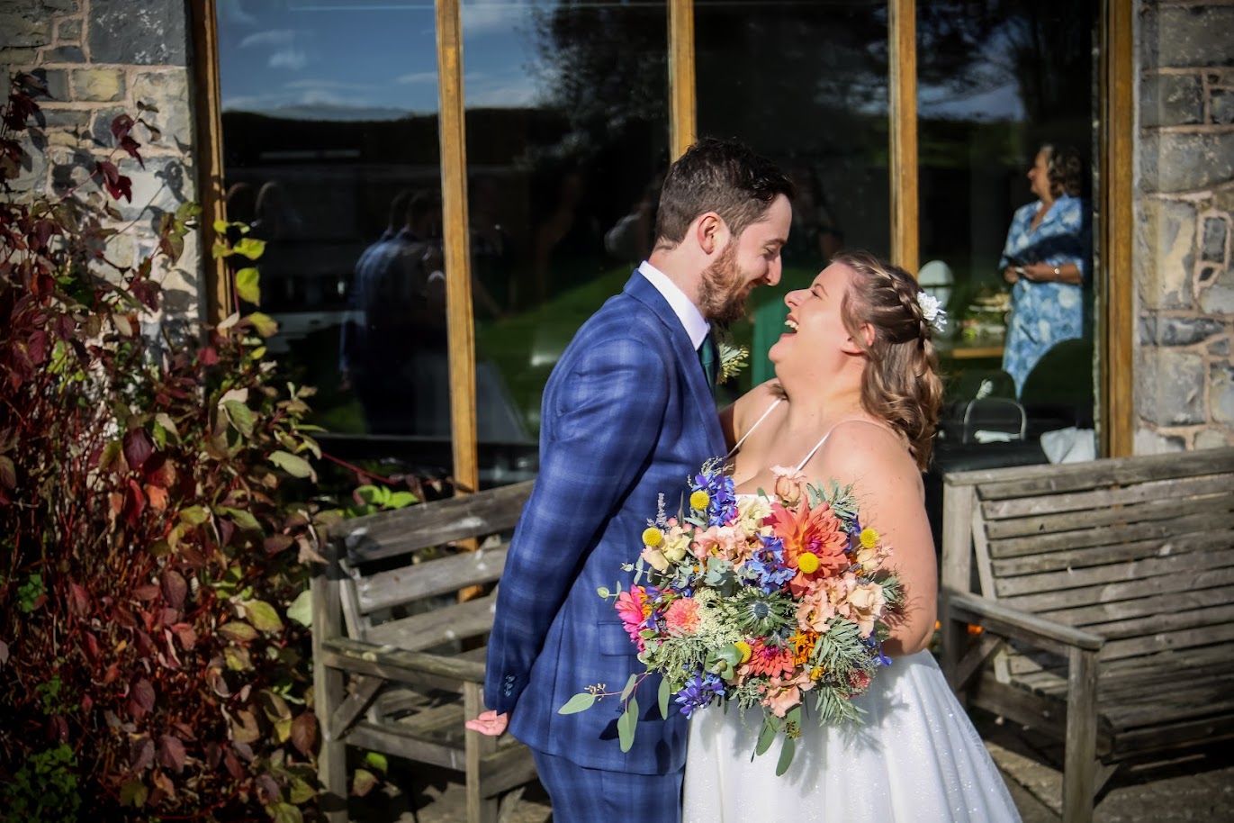 Newlywed couple kissing while holding a colourful summer wedding bouquet at Rosedew Farms