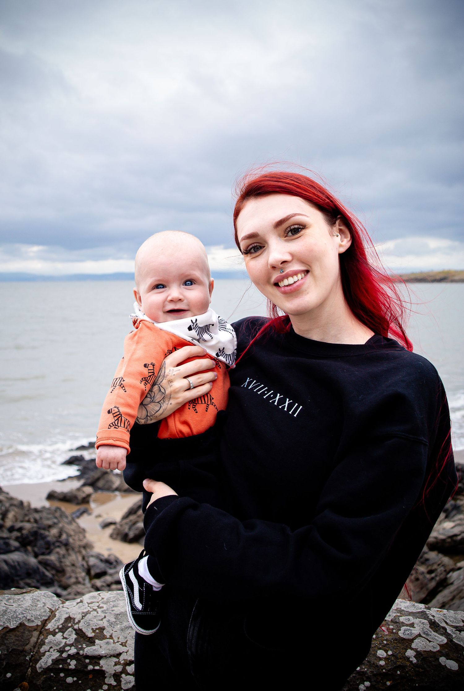Mother and baby smiling together beside the Barry Island coastline