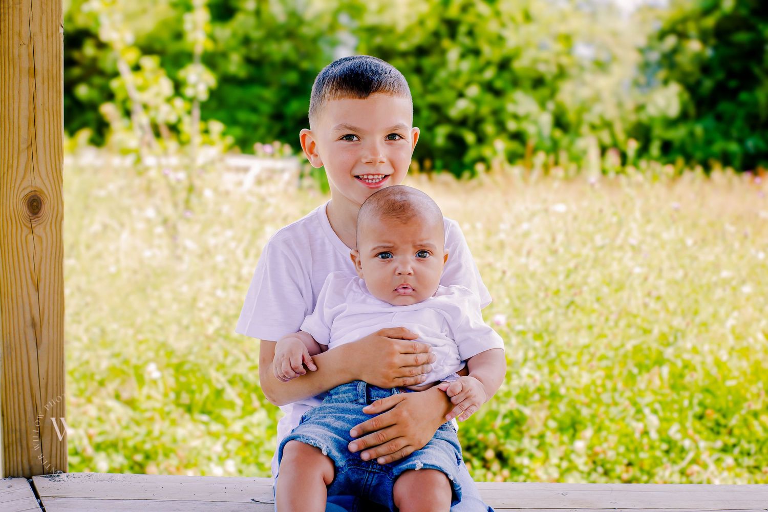 Young boy holding his baby brother sibling during an outdoor family photoshoot at Cosmeston Lake, Penarth