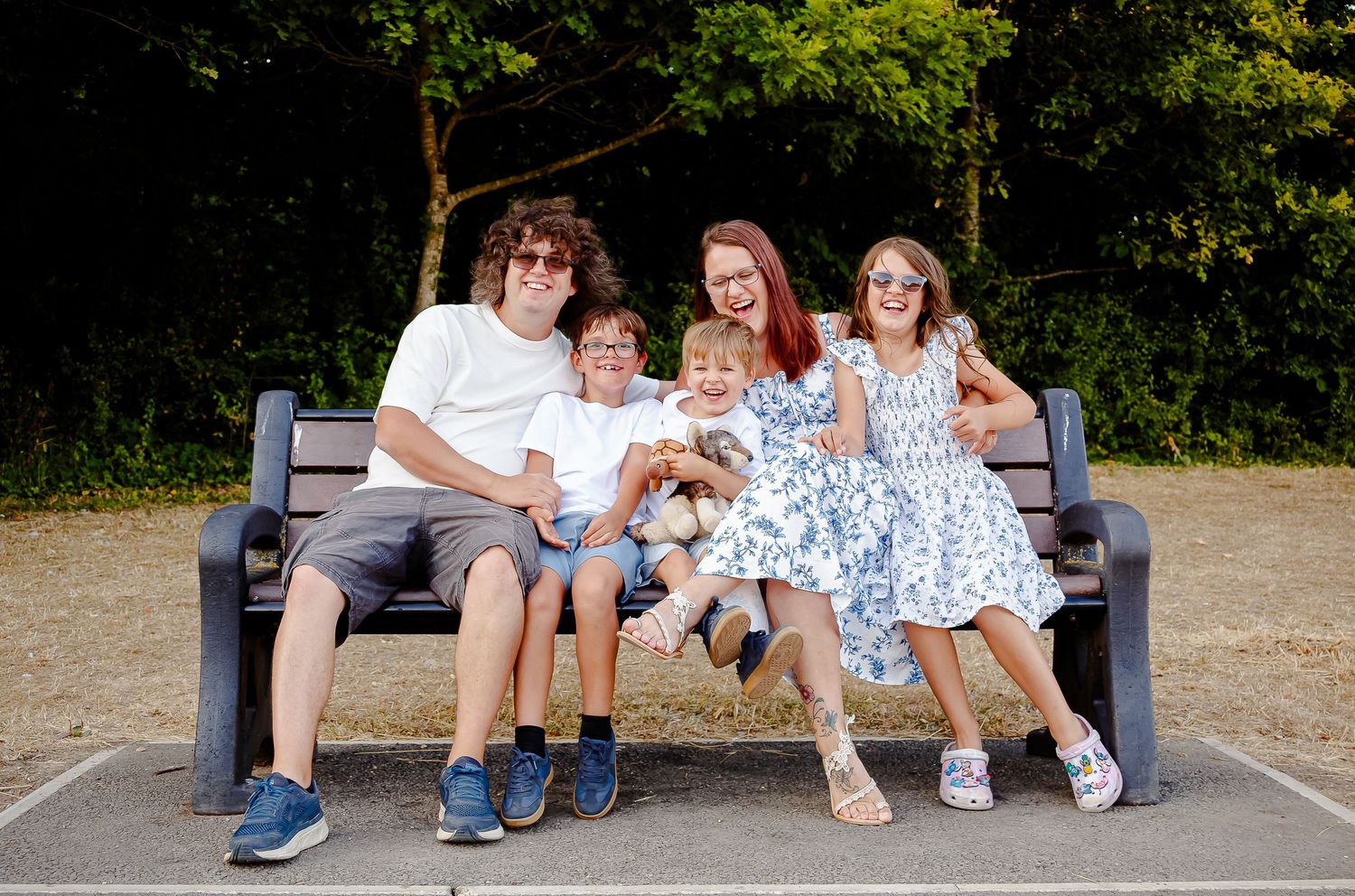 Family of five laughing together on a bench at Cosmeston Lakes