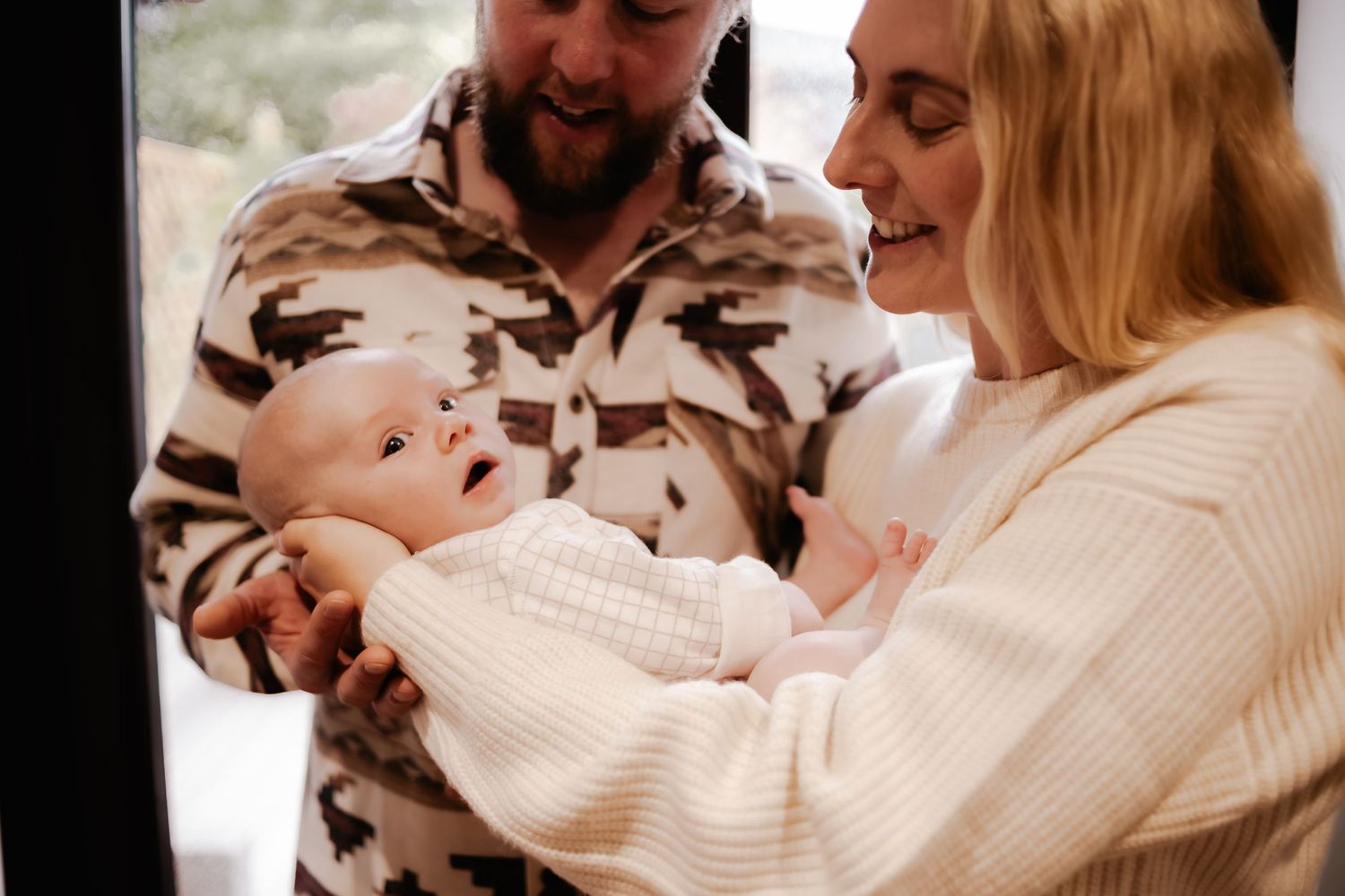 New parents cuddling their baby during an at-home newborn session