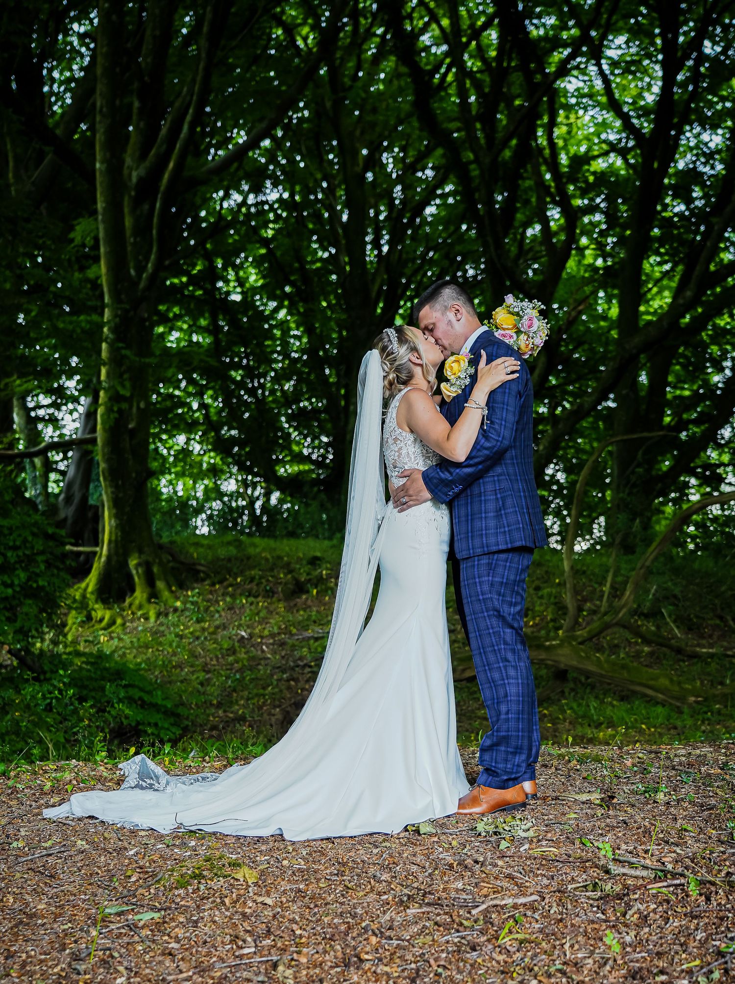 Full-length woodland wedding portrait of the bride and groom