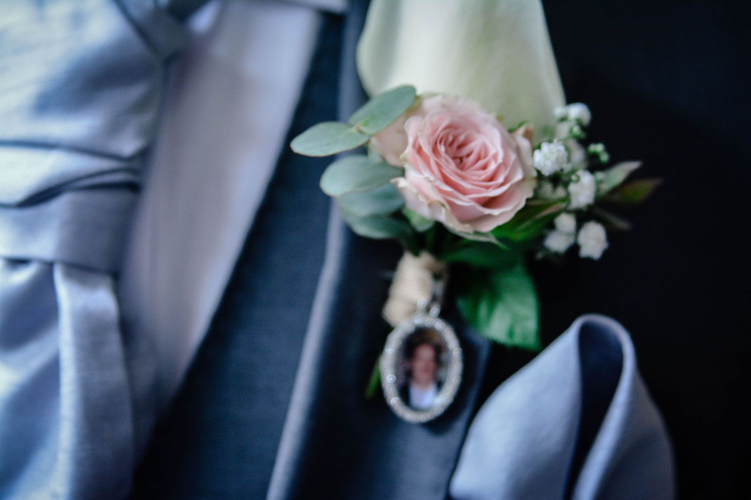 Groom’s blush rose buttonhole with a sentimental photo charm