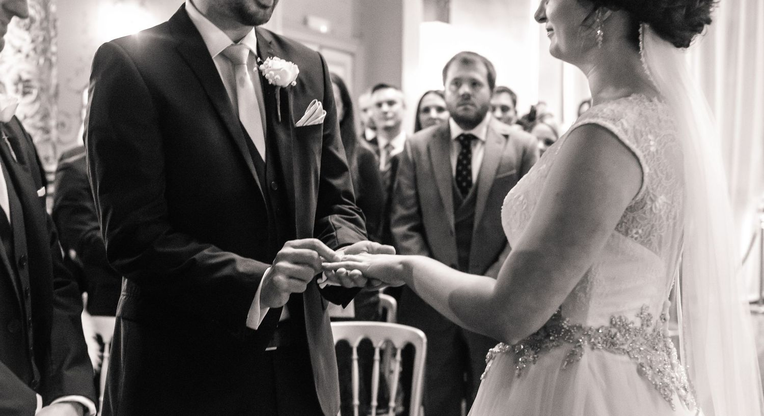 Black-and-white photograph of the couple exchanging wedding rings inside Craig y Nos Castle