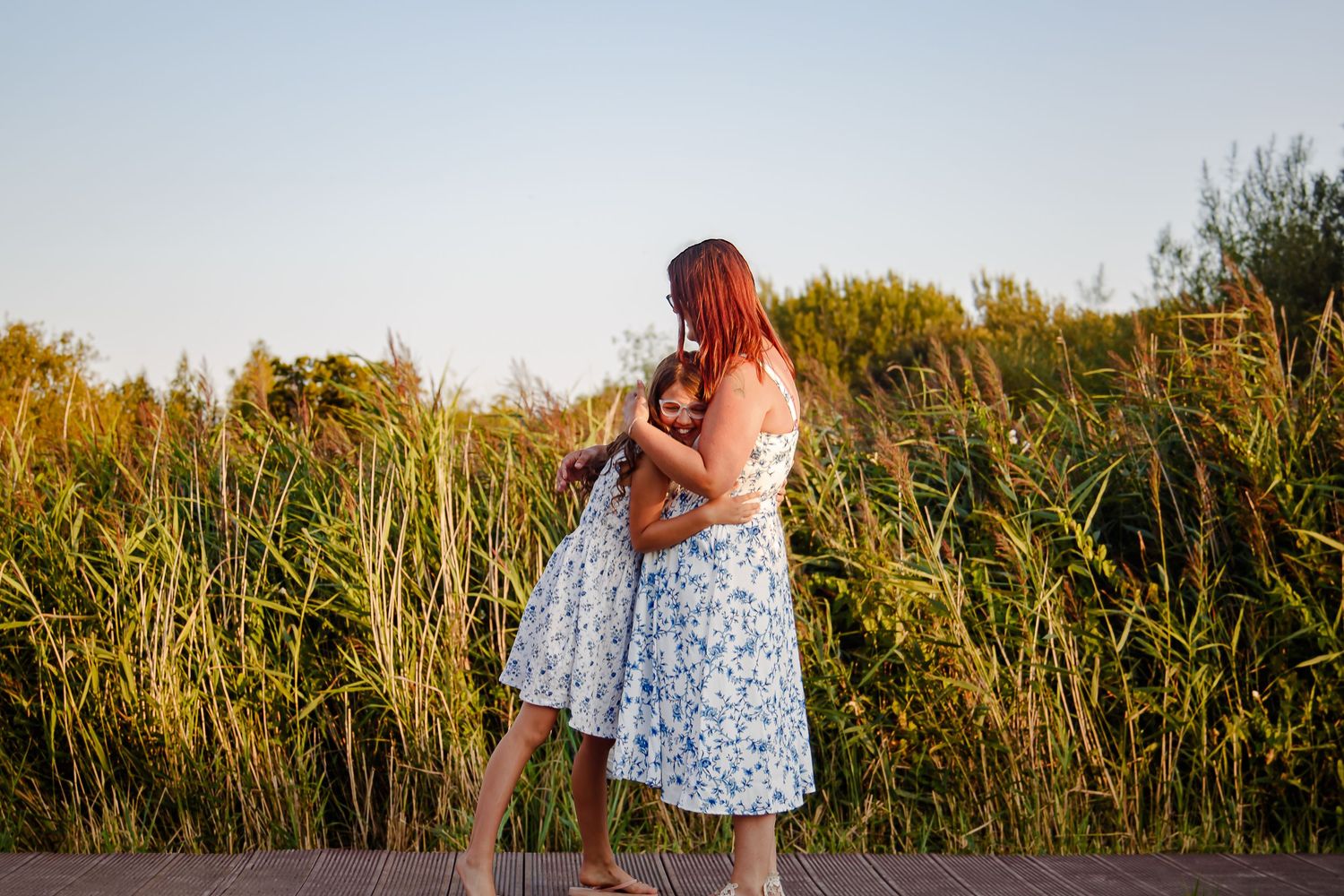Mother sharing an affectionate moment with her daughter beside the reeds