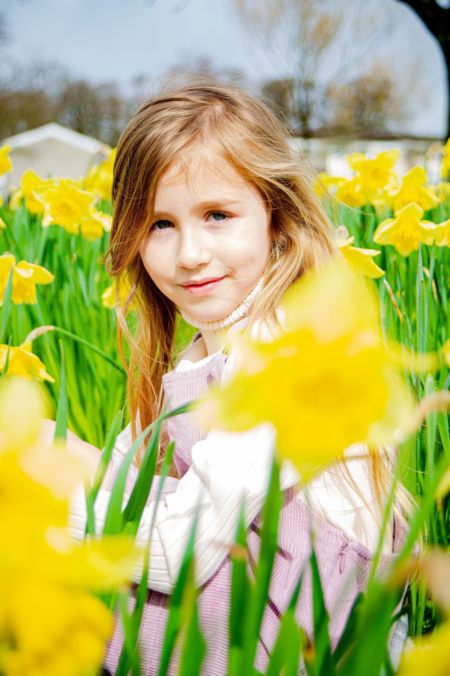Natural portrait of a young girl surrounded by daffodils