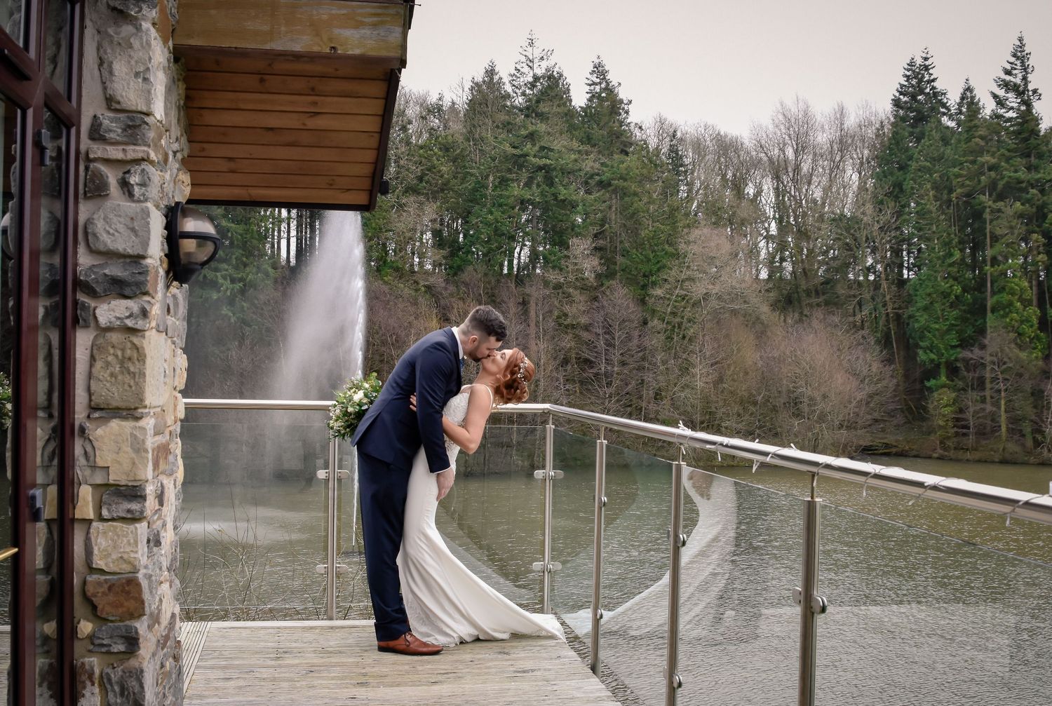 Bride and groom embracing on a balcony overlooking their woodland venue canada lodge
