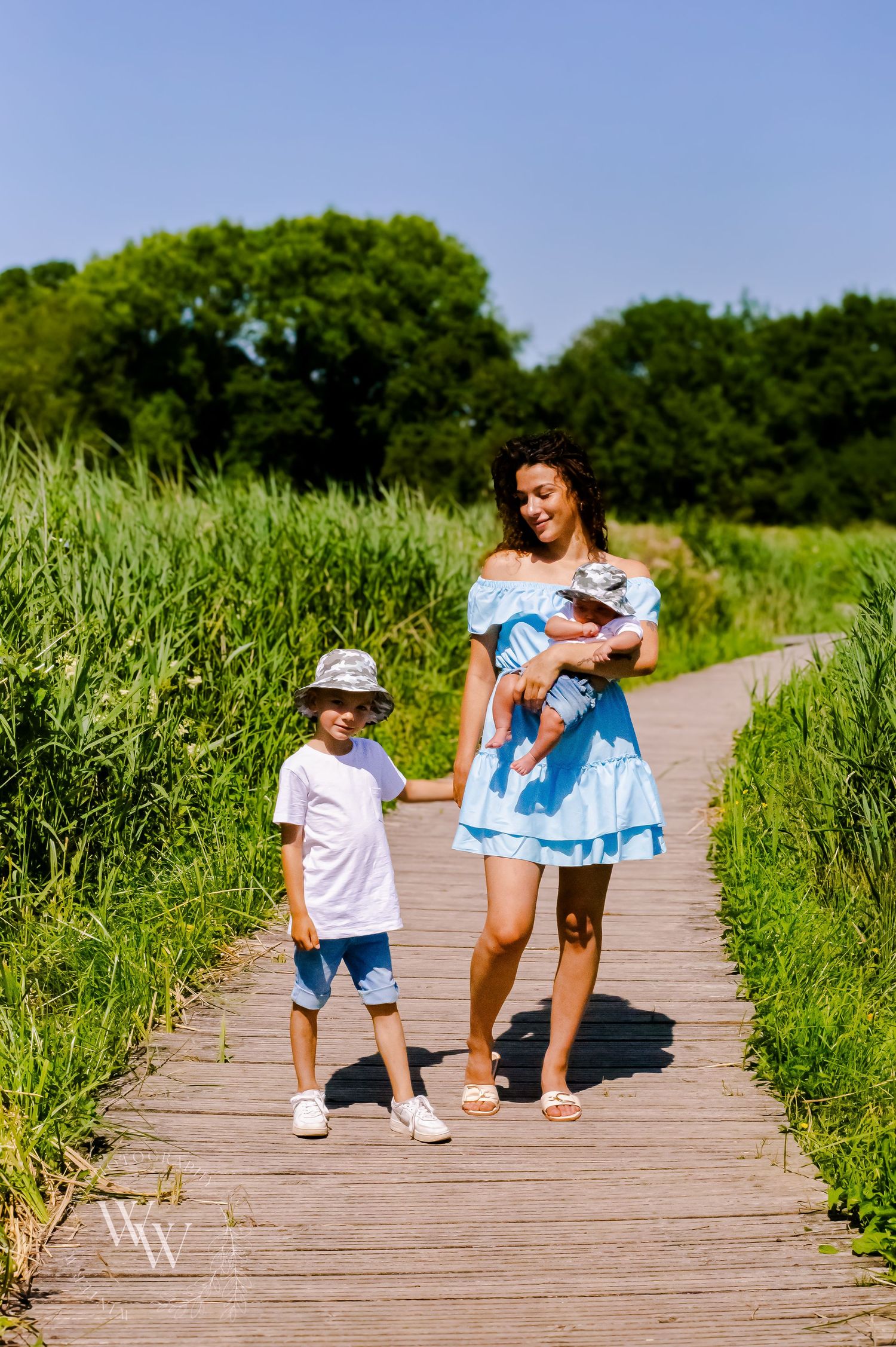 Mother and young son walking hand in hand along a woodland path at Cosmeston Lake, Penarth