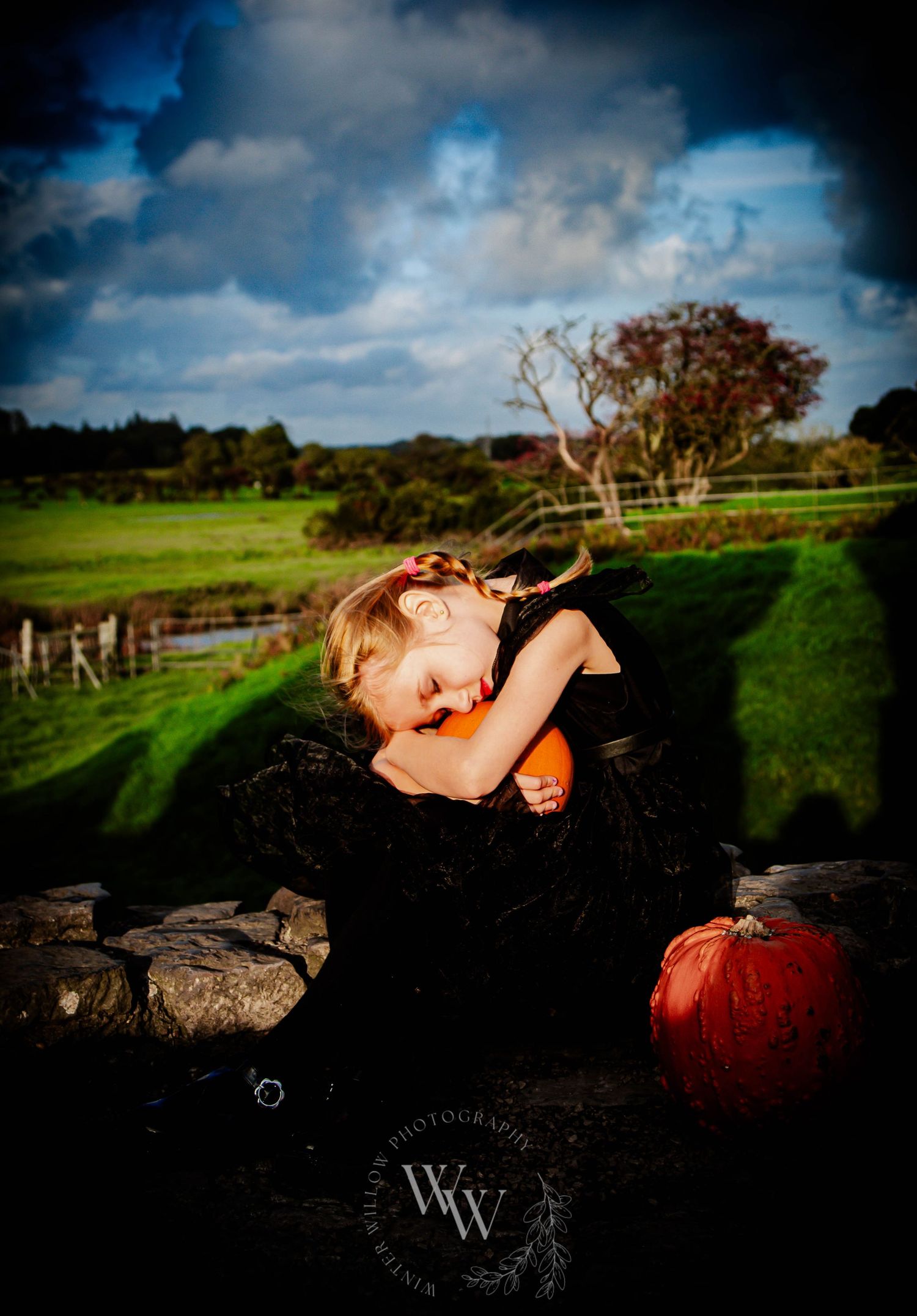 Storybook-inspired portrait of a child resting beside pumpkins beneath a dramatic sky