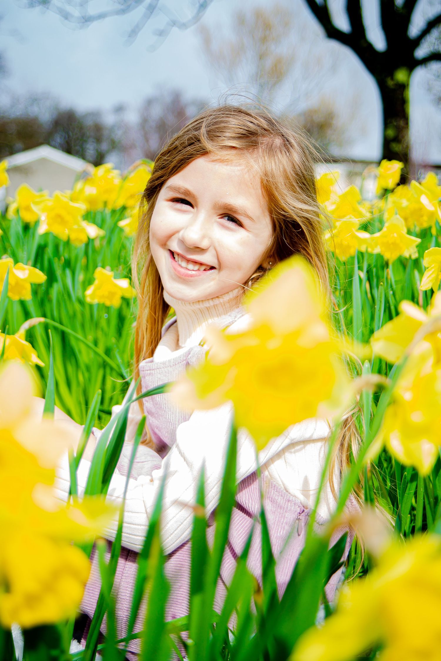 Young girl smiling among bright yellow spring daffodils