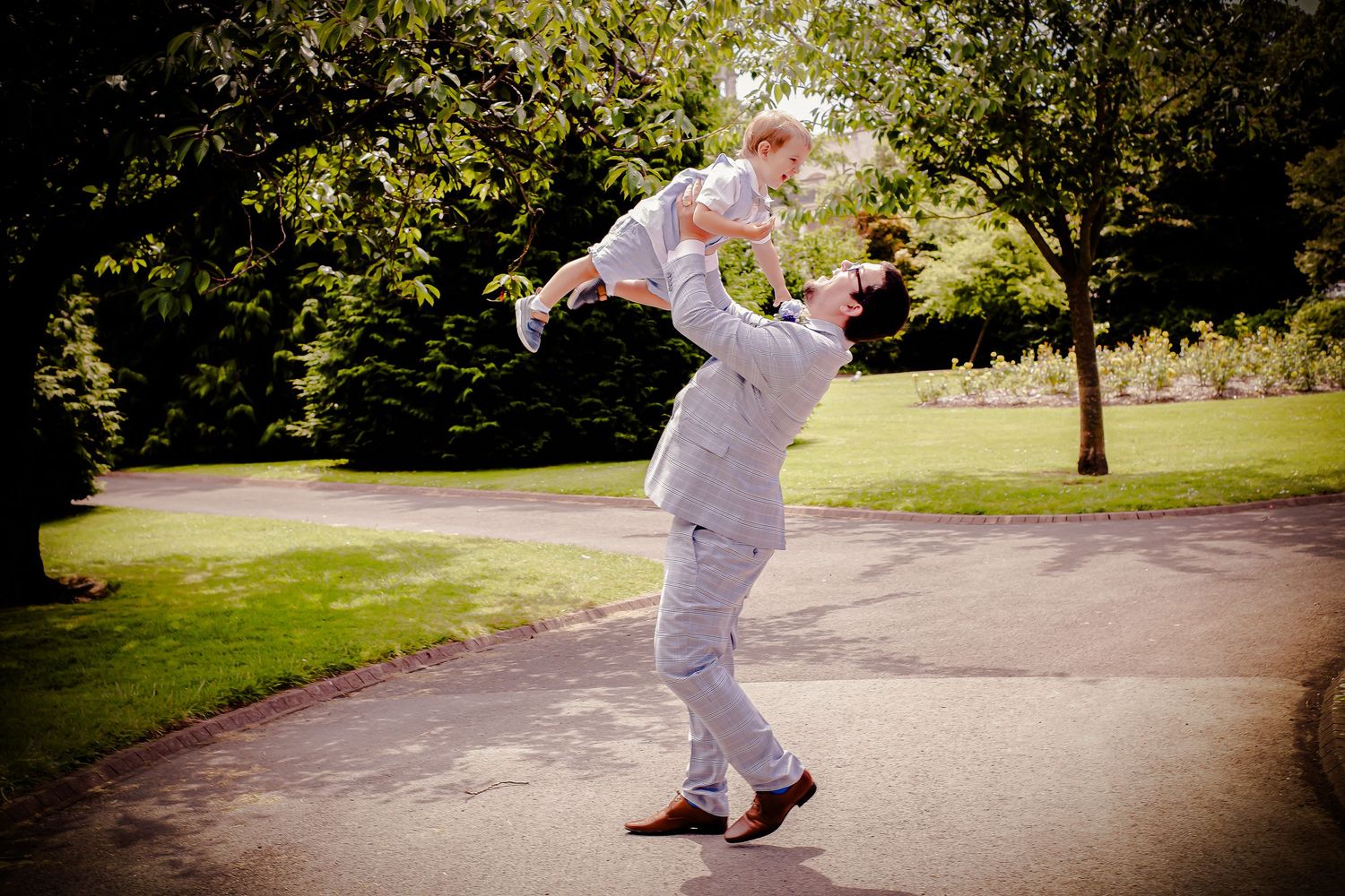 Groom giving a young wedding guest a playful up in the air hug