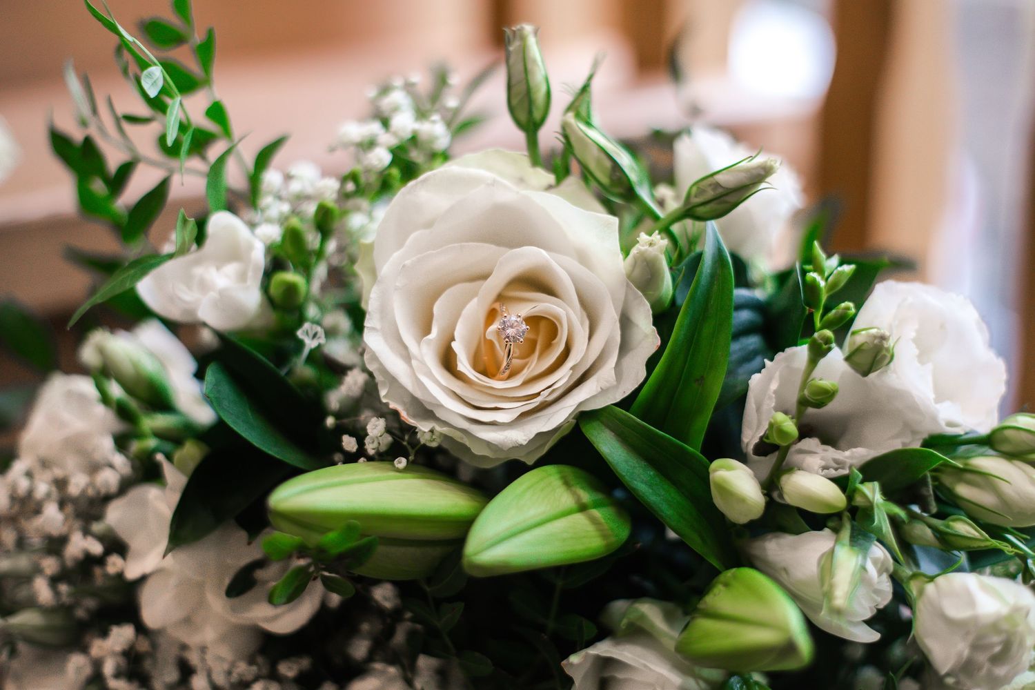 Wedding ring displayed inside white rose and lily bridal bouquet at Craig y Nos Castle