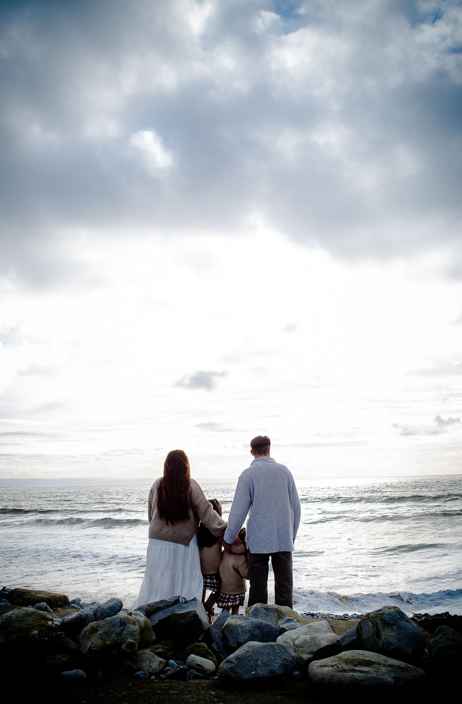 Parents standing with their daughters while looking out to sea at Southerndown