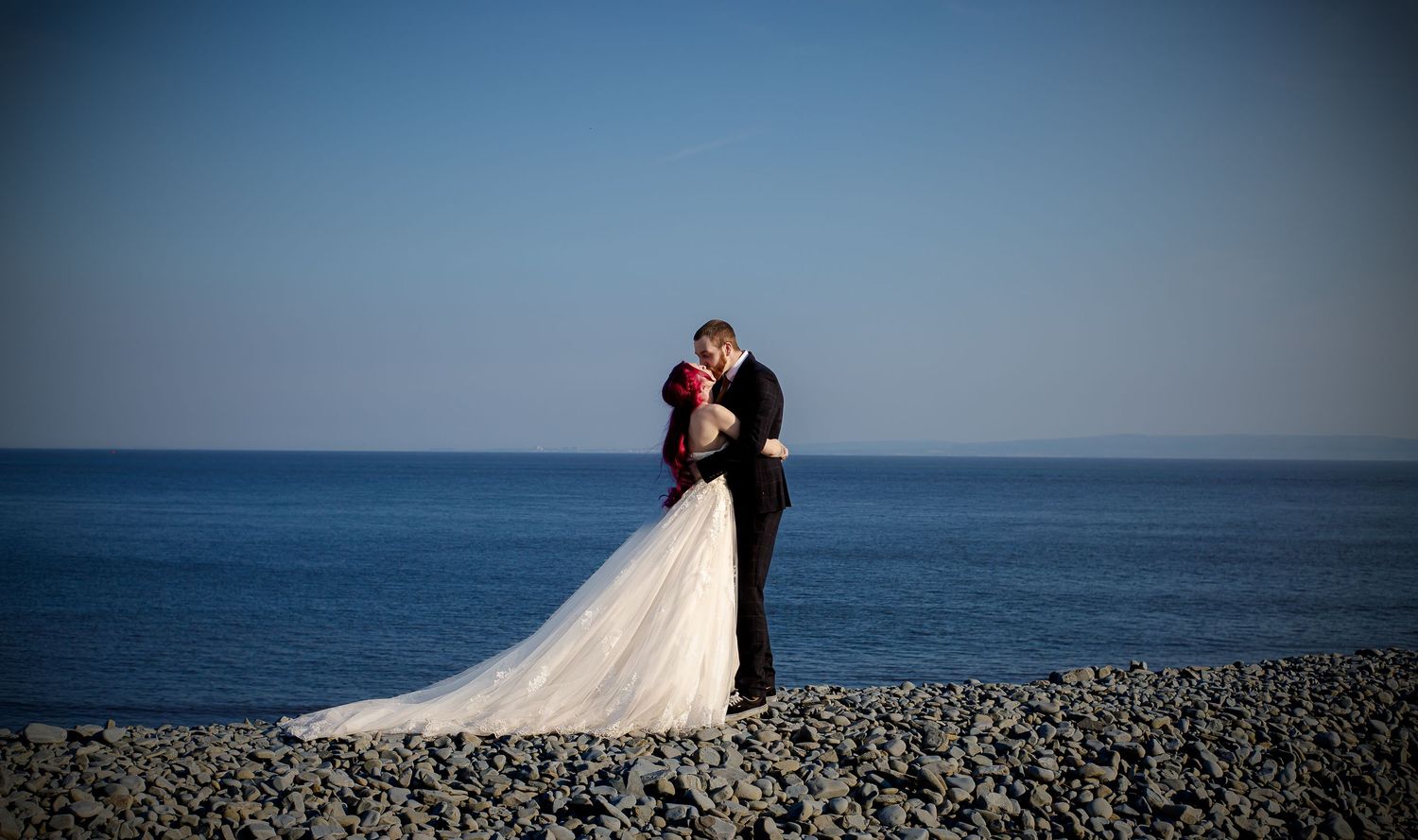 Newlyweds walking hand in hand beside the sea in Barry