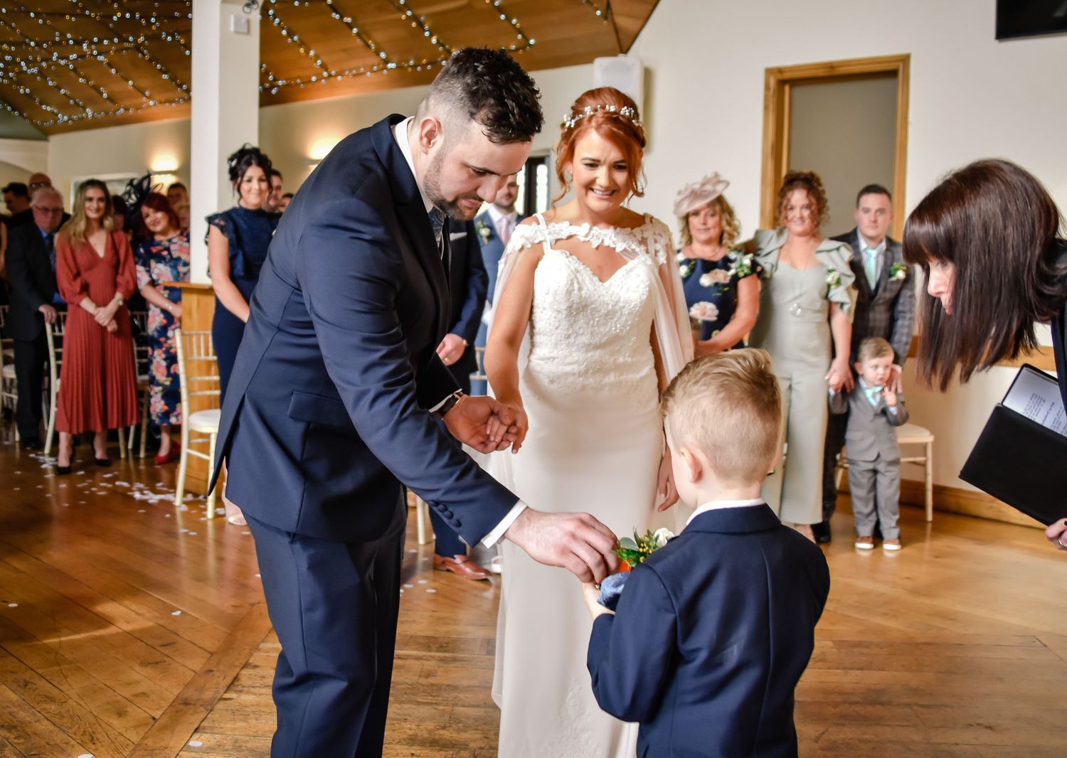 Groom receiving the wedding rings from a young page boy at Canada Lodge