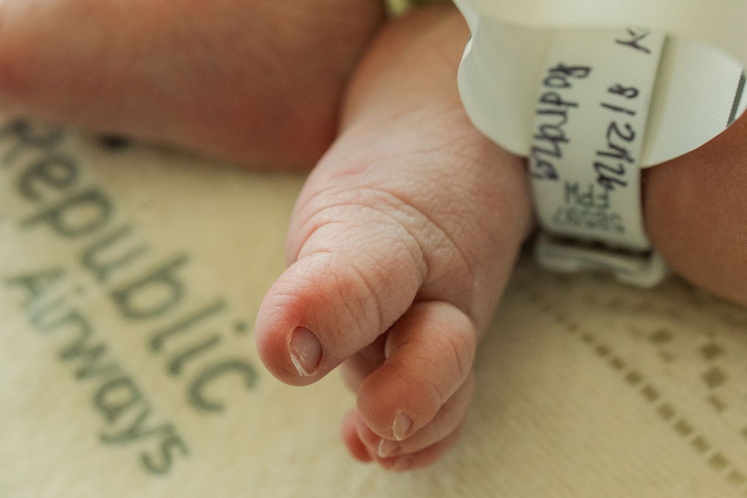 Close-up of newborn baby feet with hospital identification bracelet.