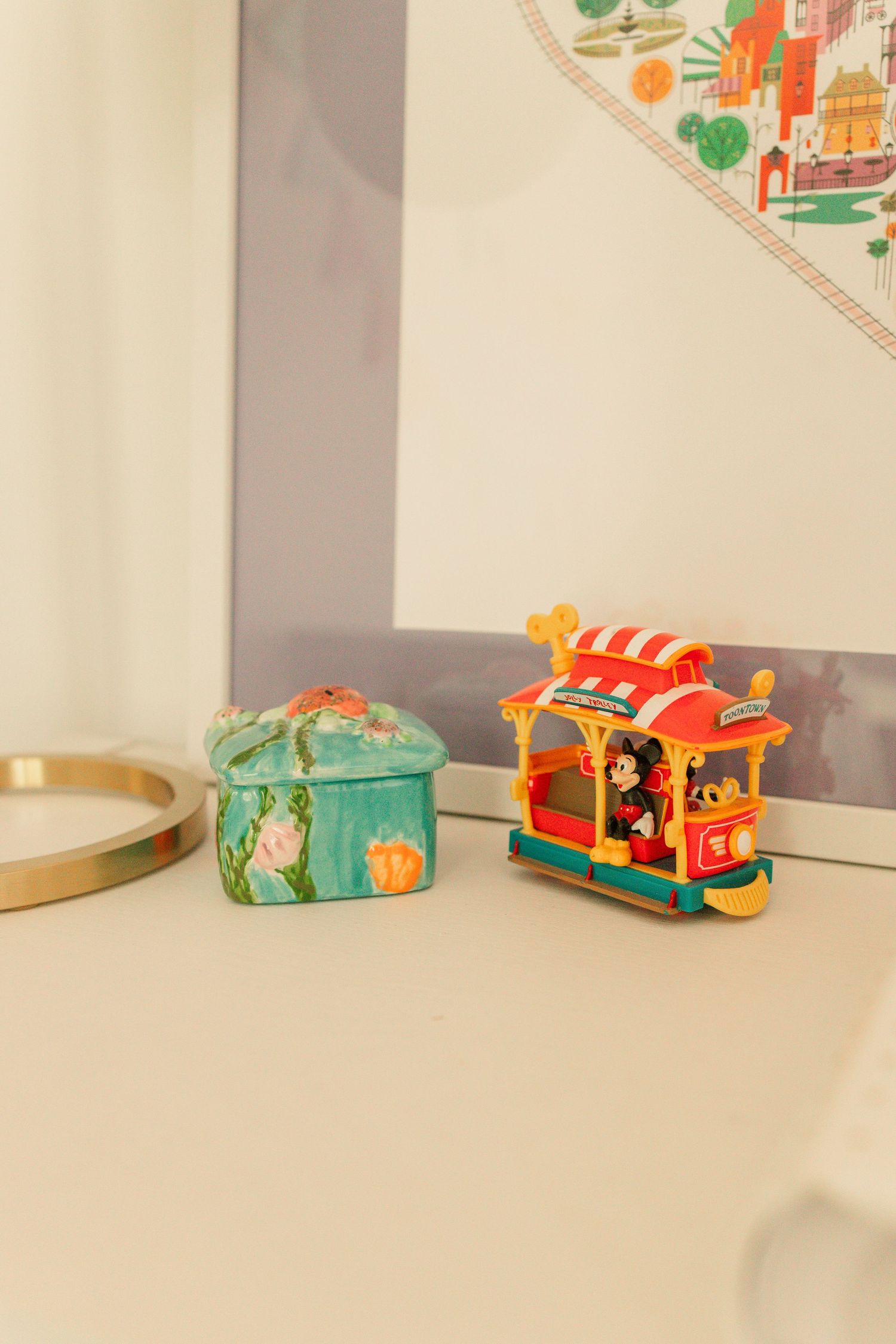 Colorful Disney Mickey Mouse trolley toy and ceramic box on a white nursery dresser.