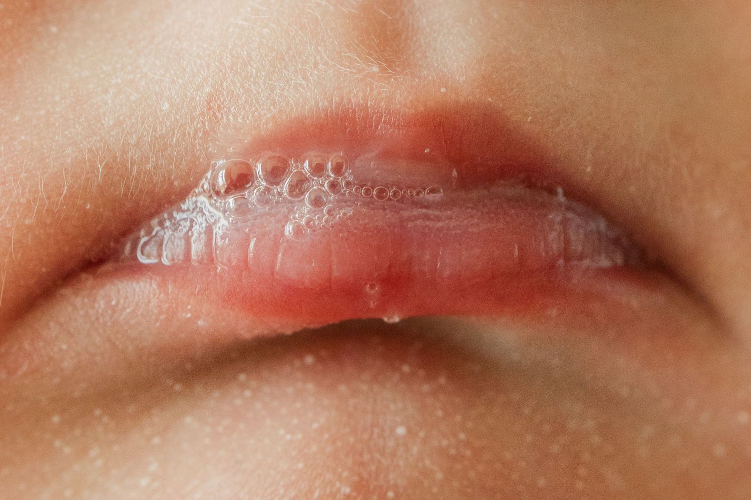 Close-up of a newborn baby's moist lips with saliva bubbles.