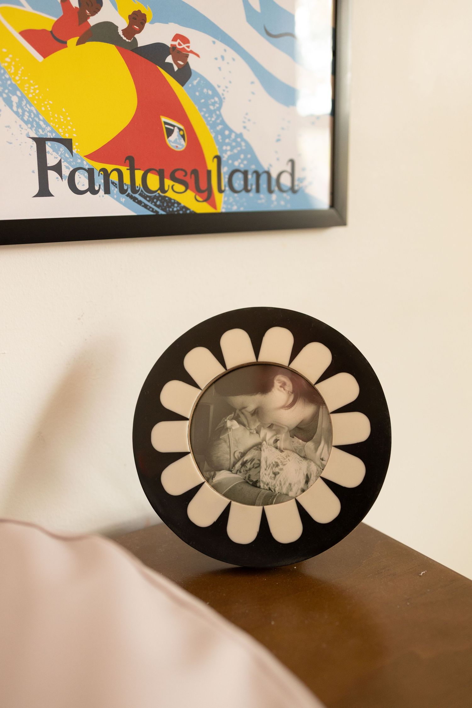 Vintage Fantasyland Disney poster displayed above a round daisy frame with newborn baby photo.
