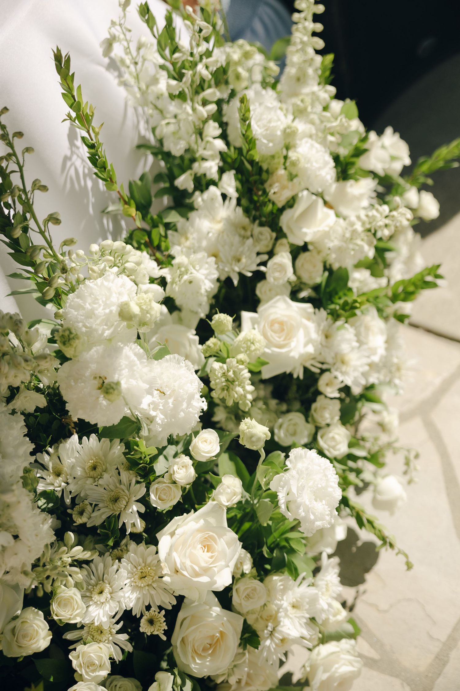Large lush wedding floral arrangement featuring white roses, chrysanthemums, and green foliage.