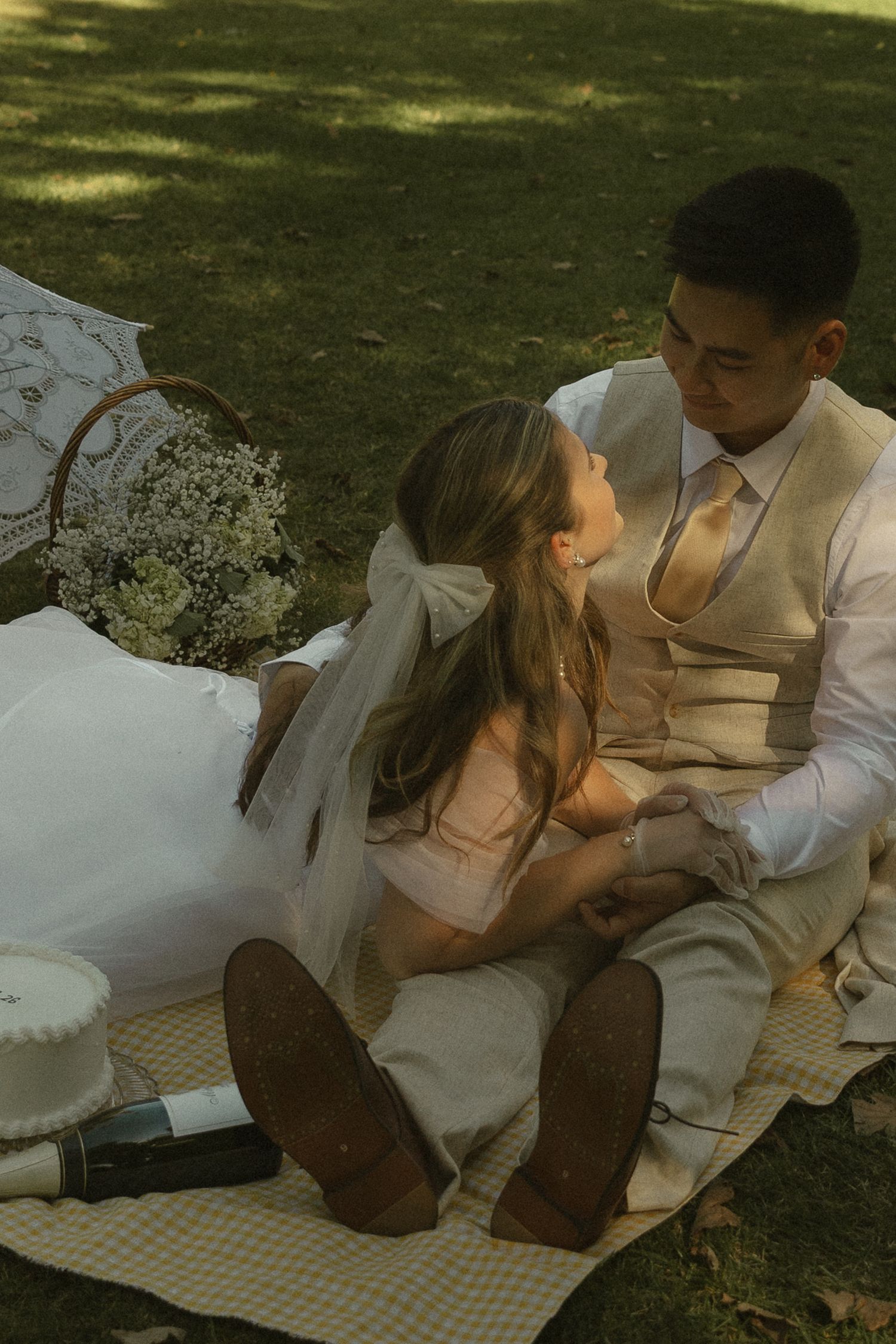 Bride and groom sharing an intimate moment during a romantic outdoor picnic on their wedding day.