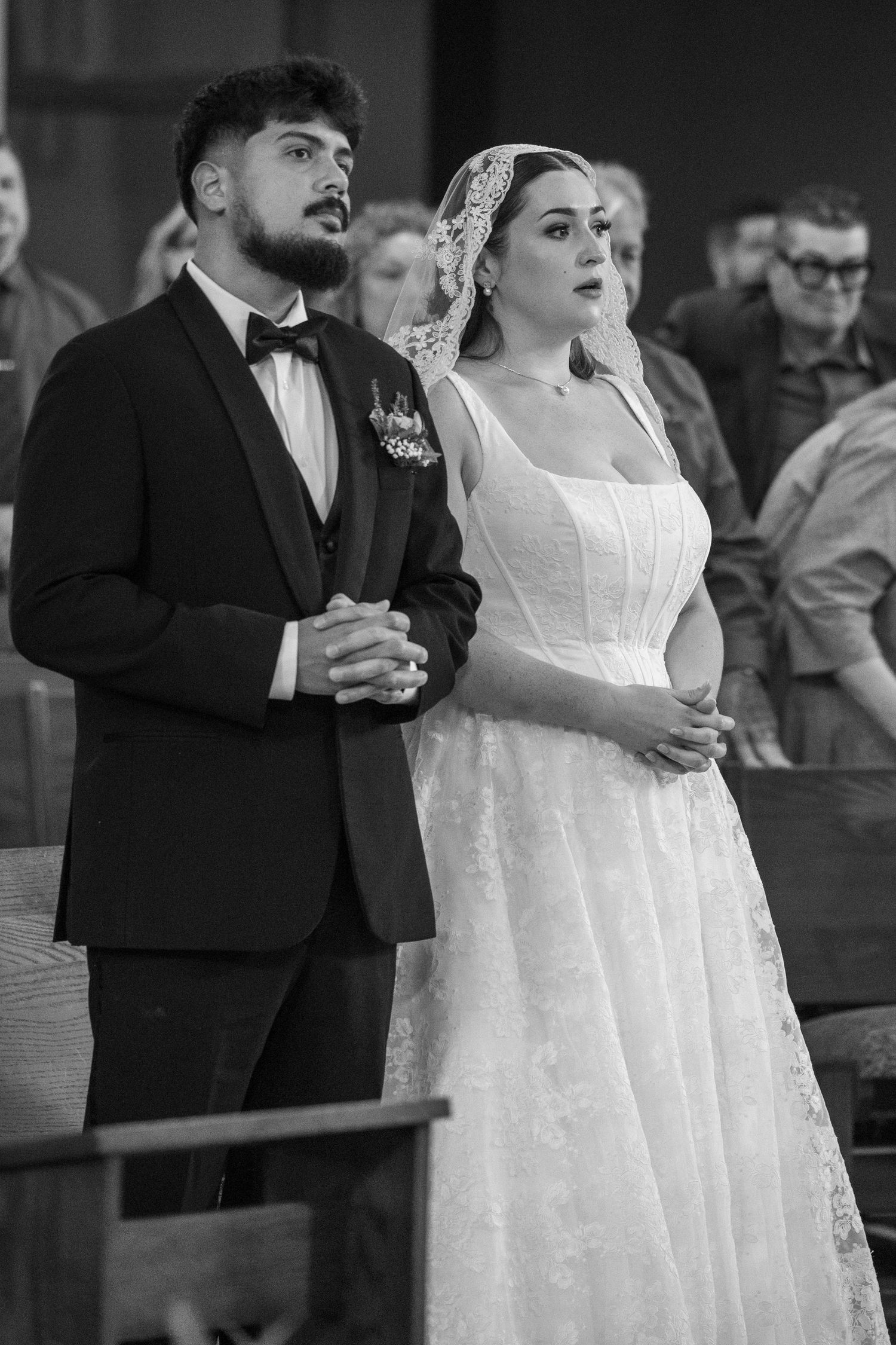Black and white photo of bride and groom standing solemnly together during their church ceremony.