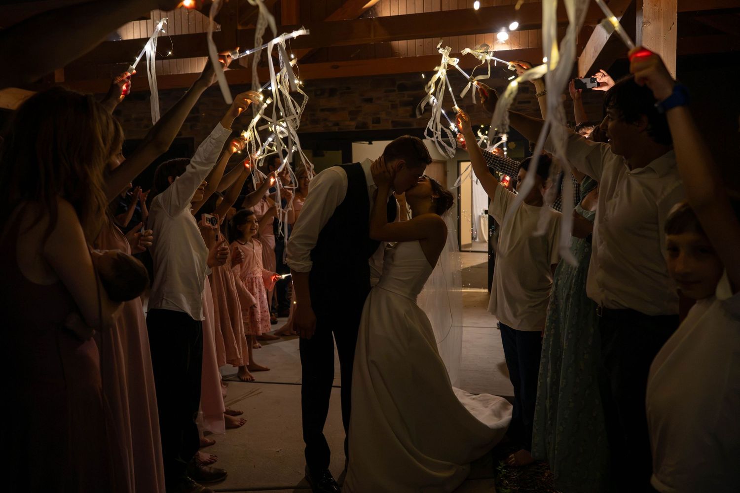 Bride and groom sharing romantic kiss during sparkler send-off exit at wedding reception.