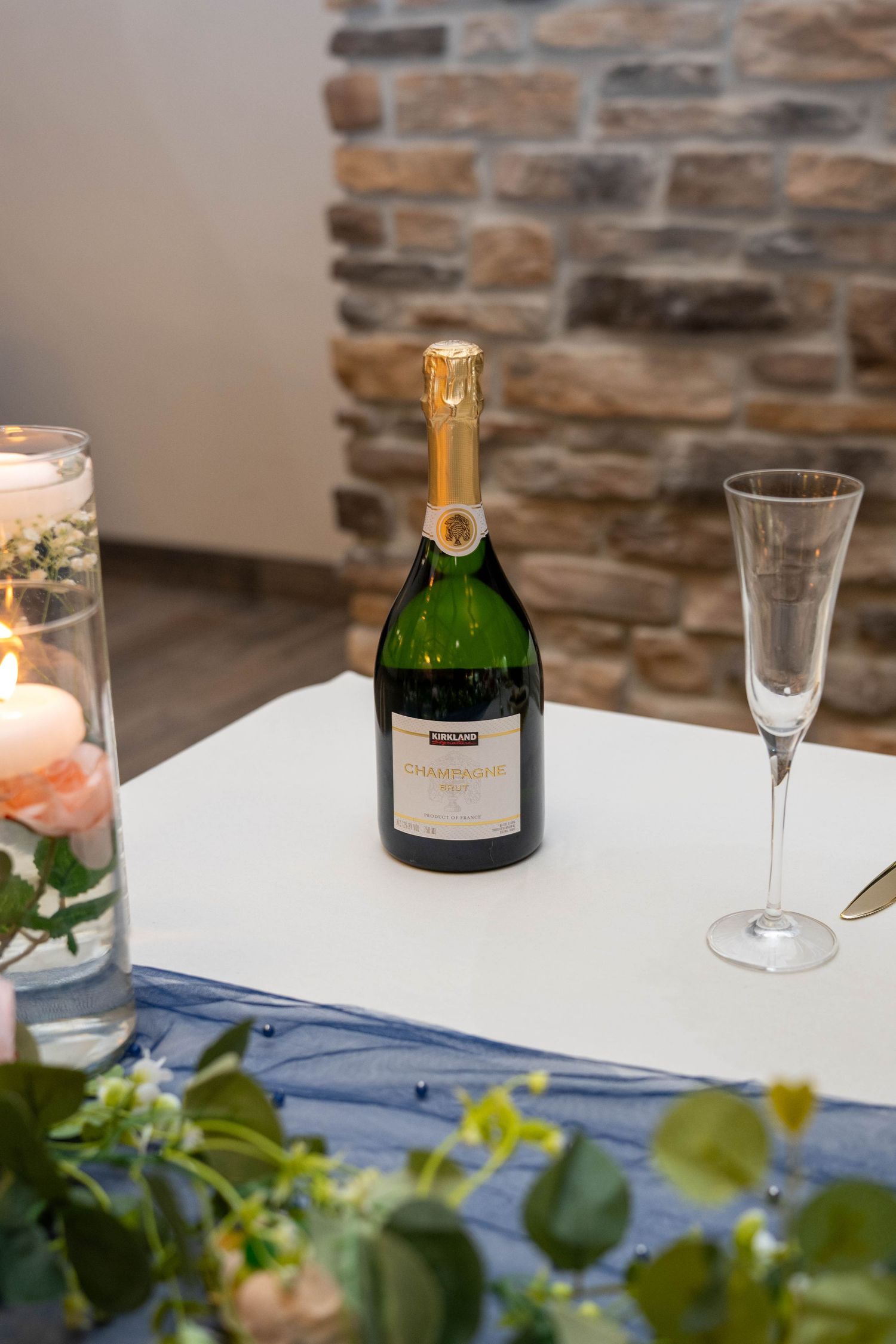 Kirkland Signature champagne bottle with flute glass on decorated wedding reception sweetheart table.
