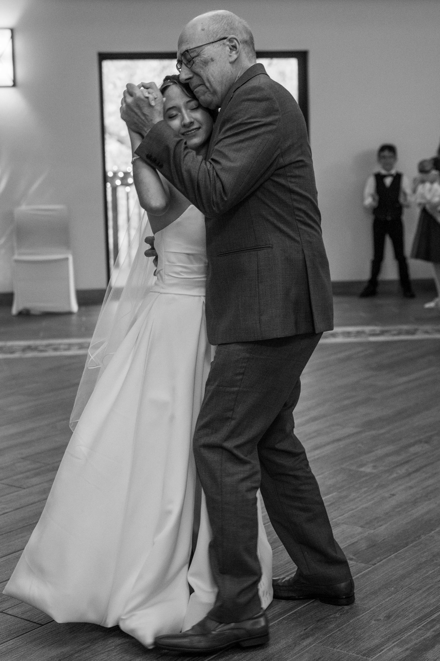 Tender black and white father-daughter dance moment captured during wedding reception ceremony.