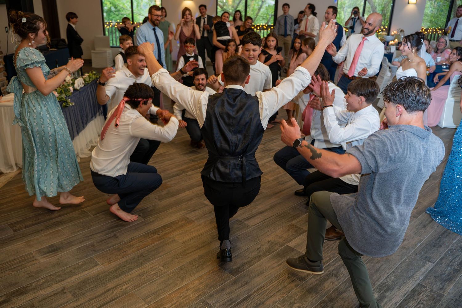 Energetic wedding reception dance floor with guests performing lively group dance moves together.