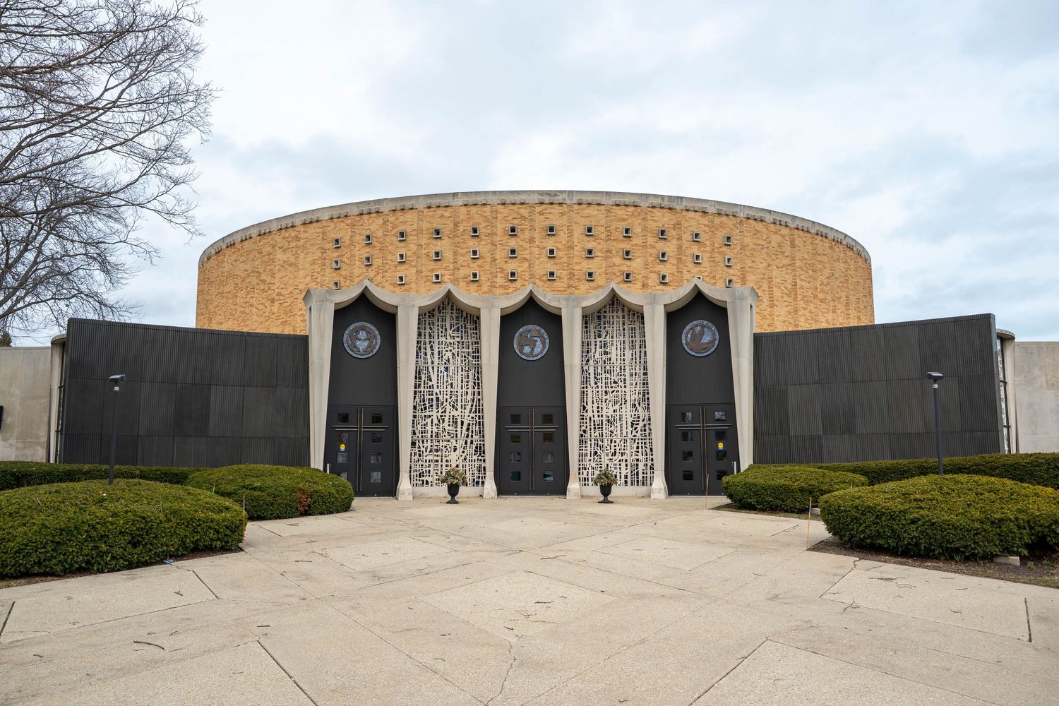 Exterior view of a grand circular brick wedding venue with ornate doors and manicured hedges.