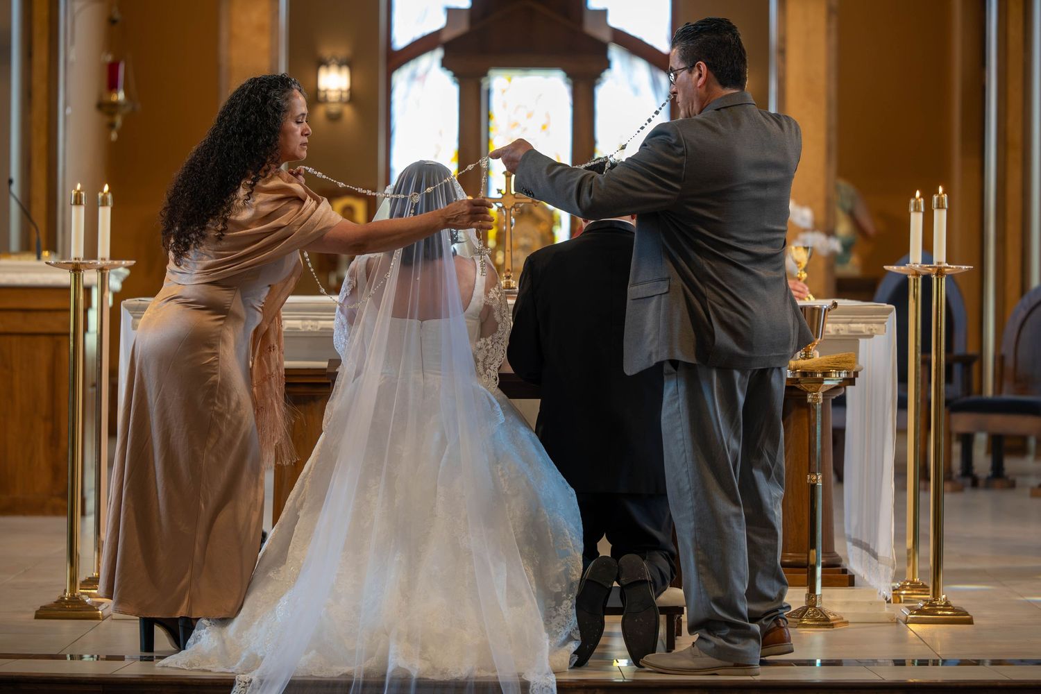 Bridesmaid adjusts bride's veil at the altar during a traditional church wedding ceremony.