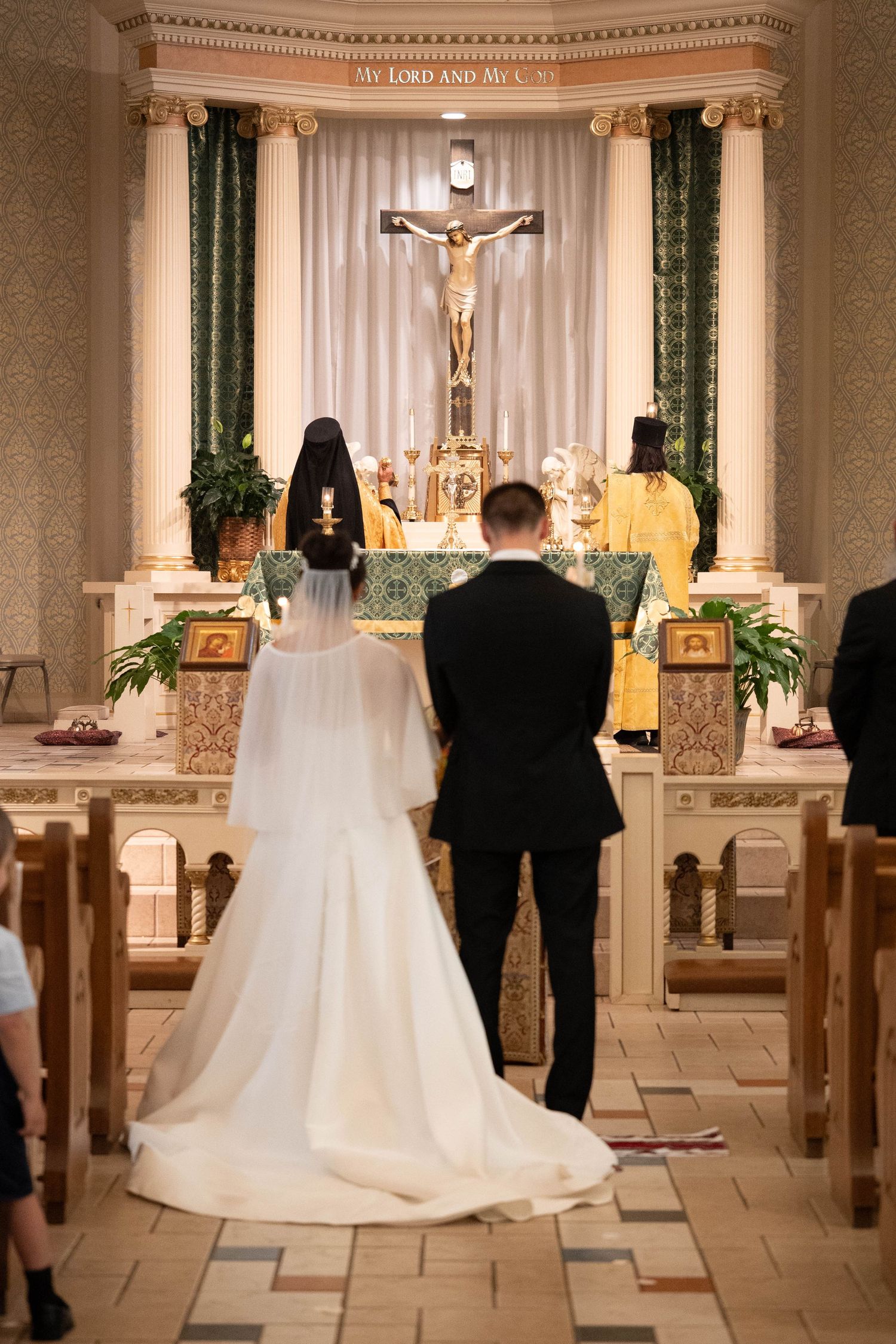 Bride and groom stand before a church altar with Orthodox priests during their wedding ceremony.