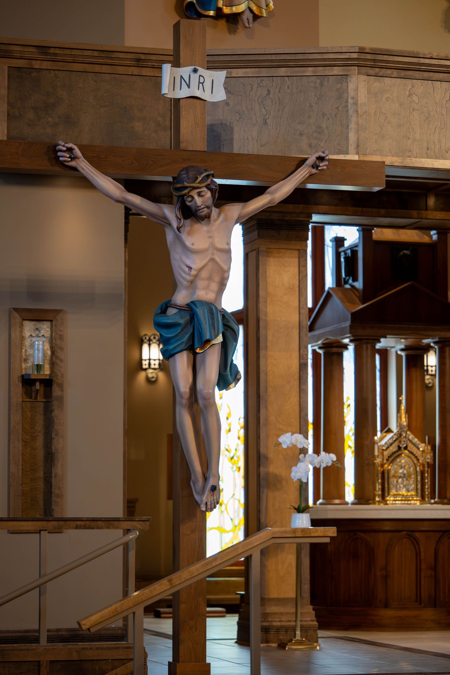 INRI crucifix statue displayed prominently in Catholic church sanctuary.