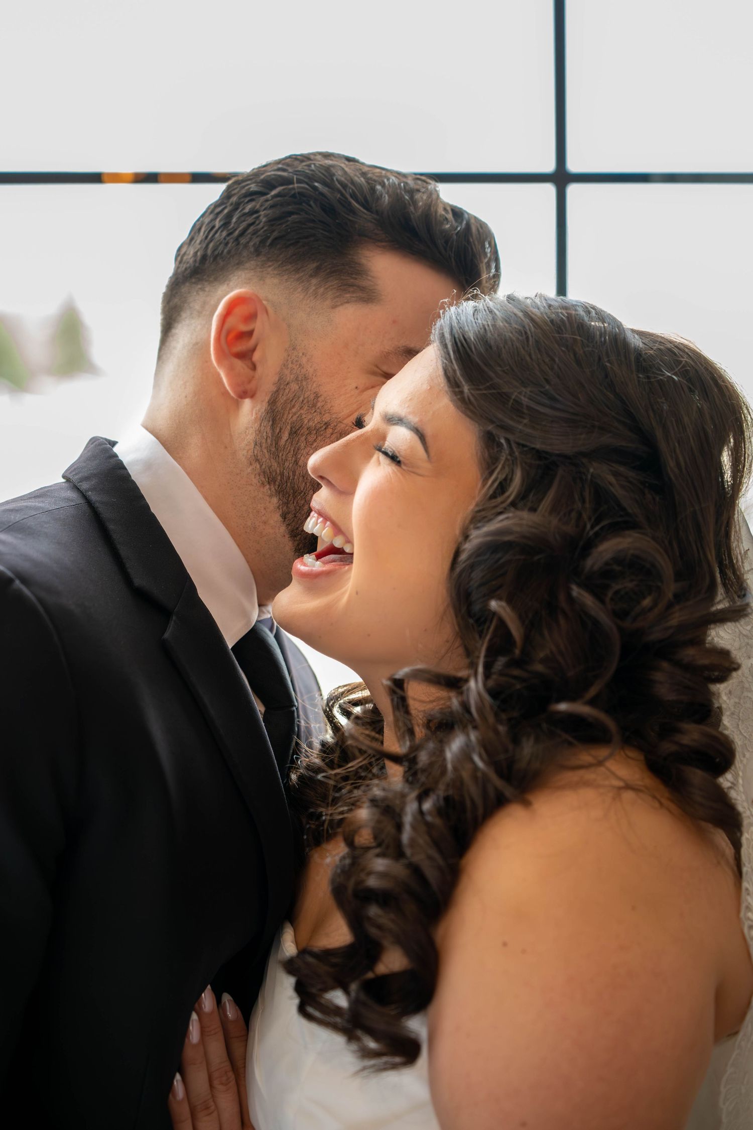 Bride and groom share an intimate moment, laughing together on their wedding day.