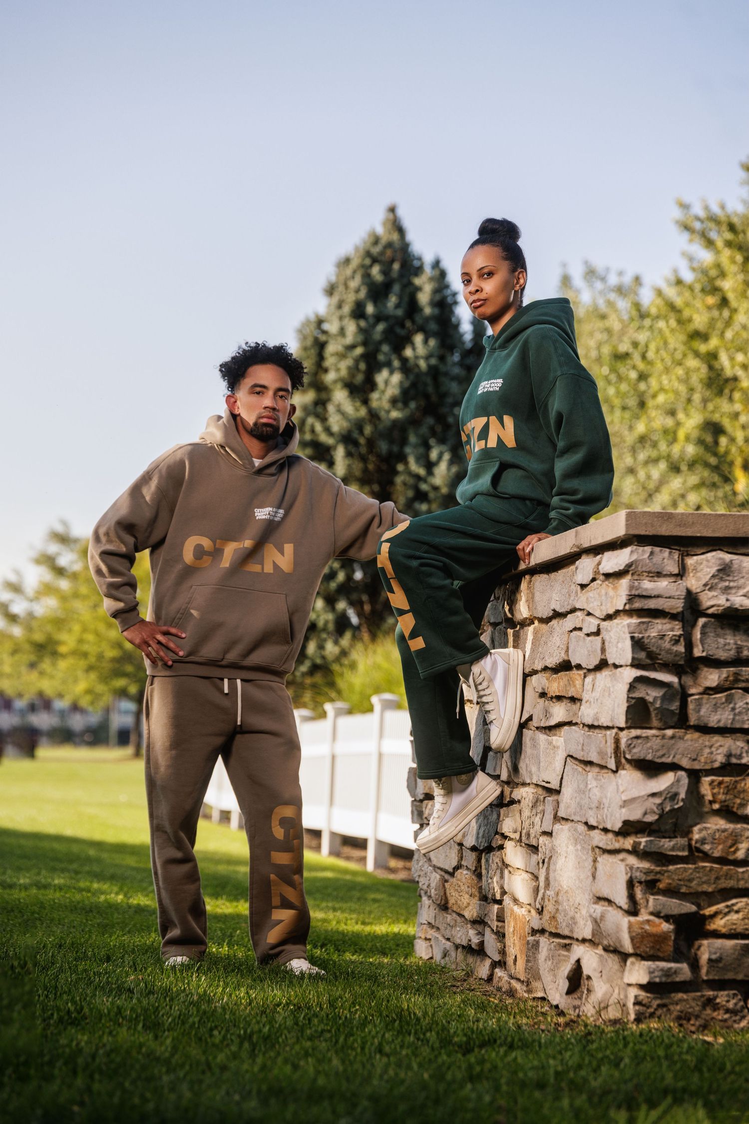 Man and woman posing outdoors in matching CZN hoodie and sweatpants streetwear sets.