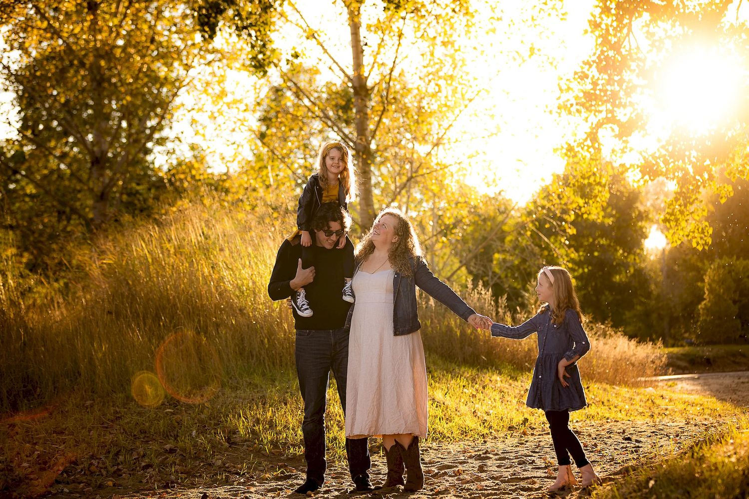 A romantic sunset photoshoot in a golden field with lens flare and tall grass creating a dreamy atmosphere.