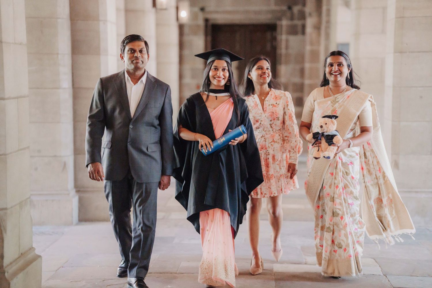 A group of wedding guests walking and chatting together in an elegant colonnade hallway.