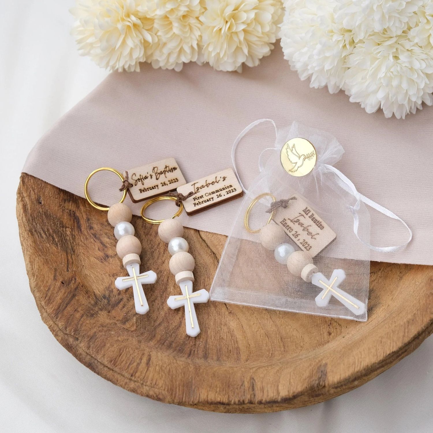 Small white wooden cross necklaces with pearl beads displayed on rustic wood slice surface for religious jewelry making.
