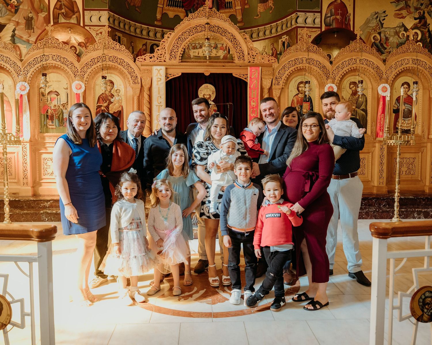 A group of people gathered inside an ornate Orthodox church with gilded iconostasis and decorative walls.
