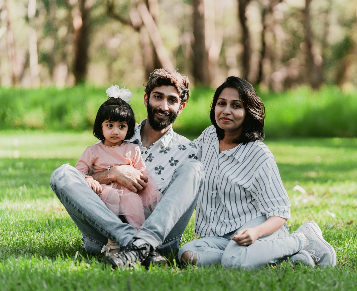 Family relaxing together on green grass in a sunny park during spring afternoon.