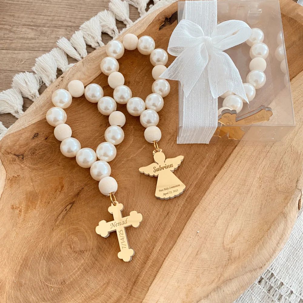 White beaded Christmas tree ornaments with cross charms laid out on a wooden surface in a decorative pattern.