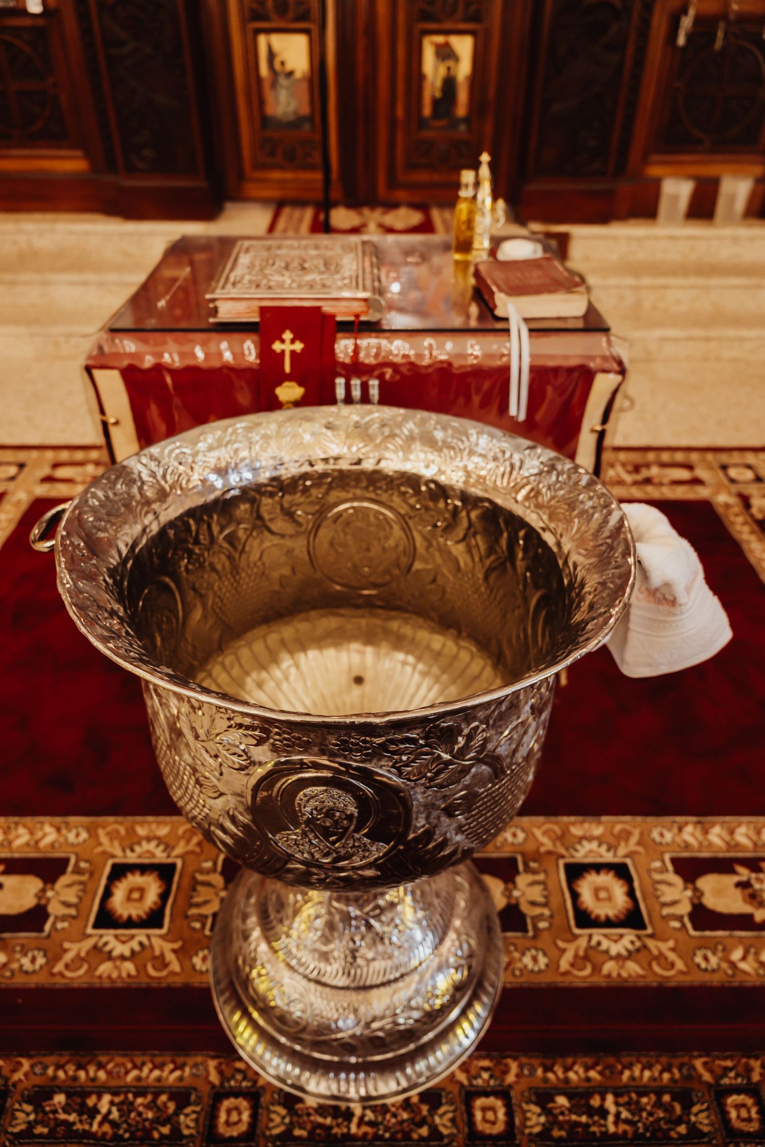 Ornate antique silver serving bowls with intricate engraved patterns displayed on a dark wooden table with red carpet.