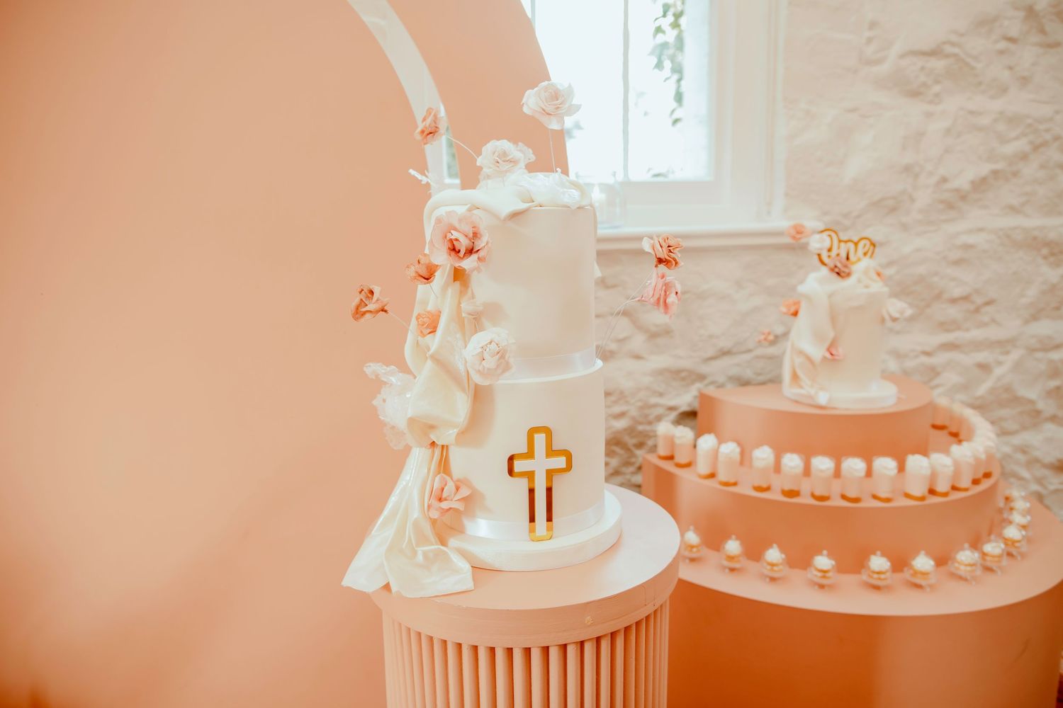 Delicate white paper rosary beads and cross arranged in a spiral pattern on a peach-colored background.