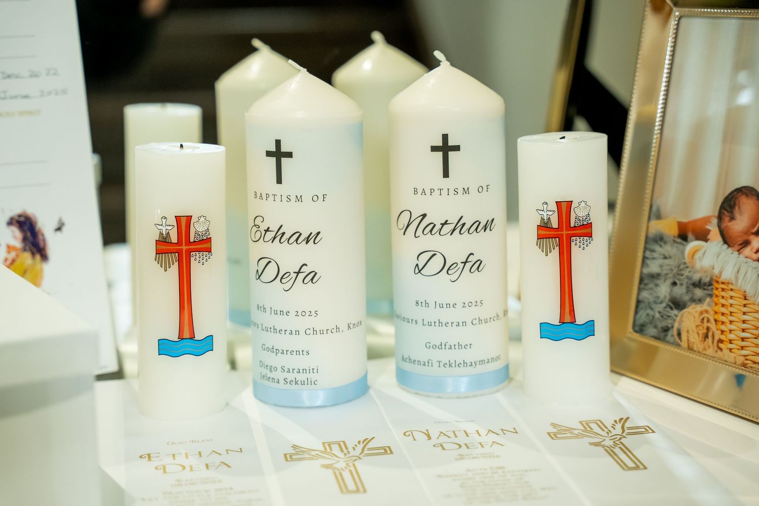 White baptismal candles with crosses and personalized names displayed together for a religious ceremony.