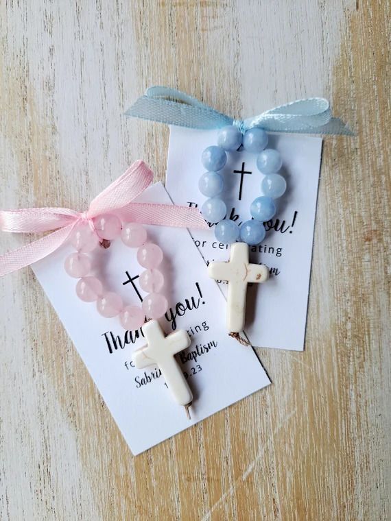 Small white thank you cards decorated with pastel blue and pink ribbon bows and delicate beaded accents on a rustic wooden surface.