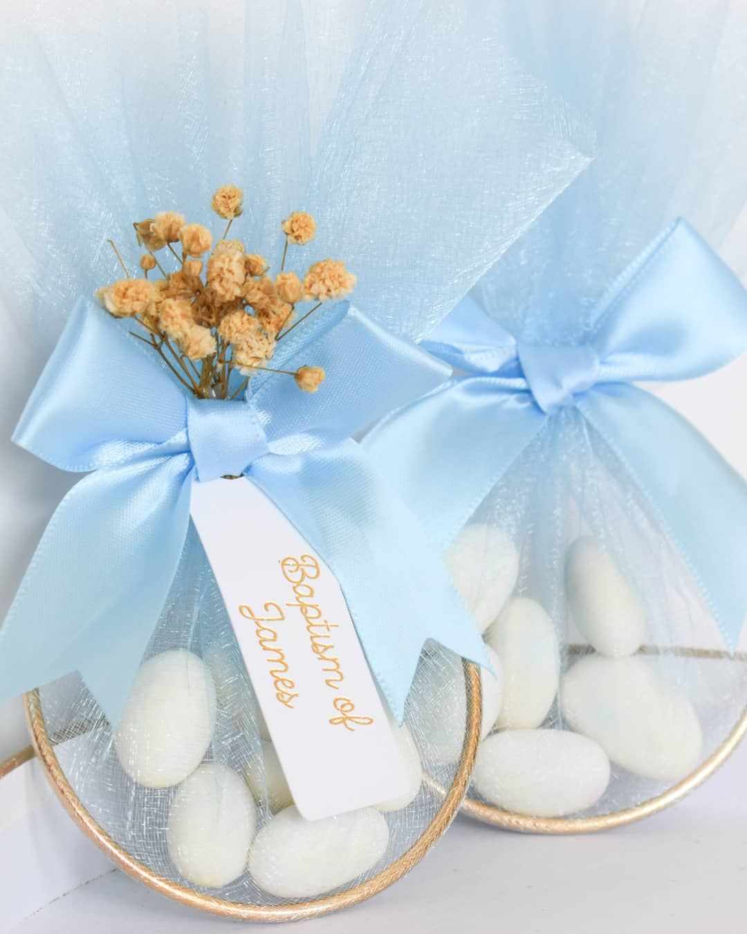 Light blue organza bags filled with white candies tied with matching ribbons and tags on delicate china plates.