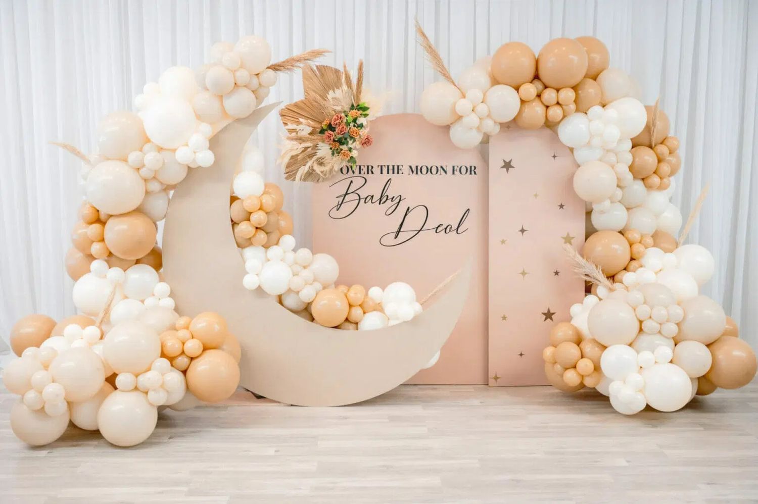 Elegant white and gold balloon garland arch with pearl balloons decorating a wedding backdrop wall.