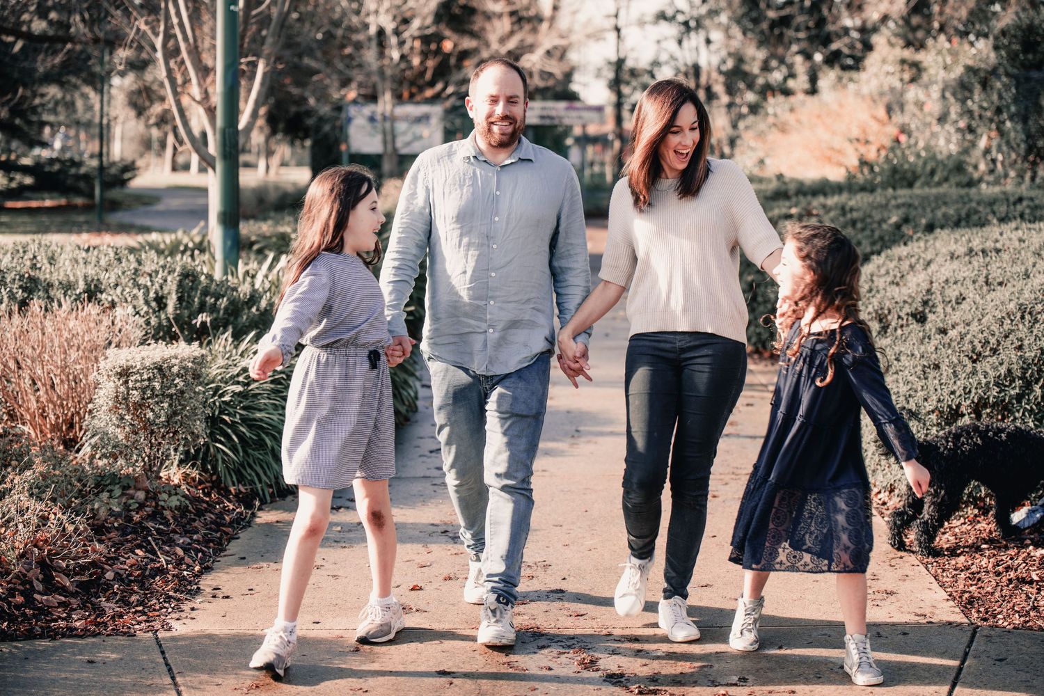 A group of people walking together on a sidewalk in a park setting during sunset.